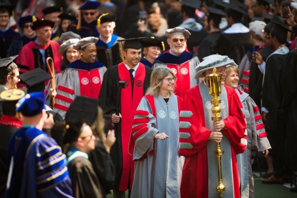 President Kornbluth (center of photo) smiles and marches towards the stage with faculty from MIT's five schools behind her.