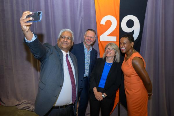 President Kornbluth stands and smiles with other senior leadership in front of a 2029 banner.