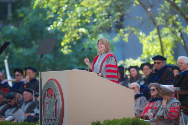 President Kornbluth stands behind a podium on stage and delivers graduation remarks. 