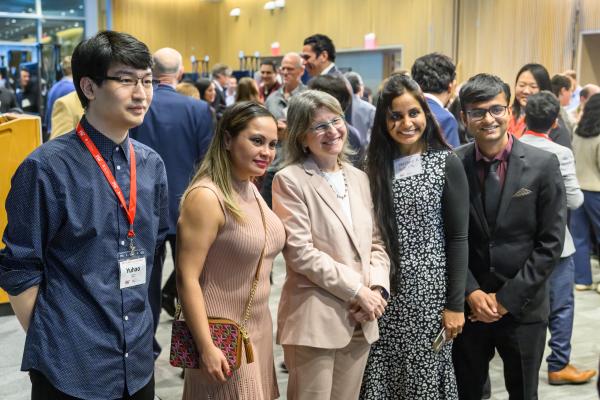 Standing in the center of a group of four students, President Kornbluth smiles with students during an MIT CTL Research Expo photo op.
