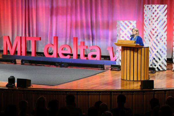 President Kornbluth stands behind a podium and speaks at MIT delta v Demo Day.