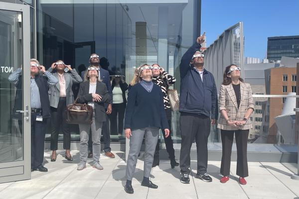 President Kornbluth stands among a group and views the April 8 2024 solar eclipse.