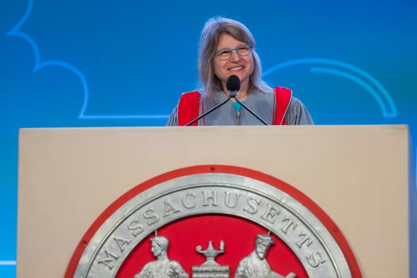 President Kornbluth smiles standing behind a podium as she delivers her Inaugural Address.