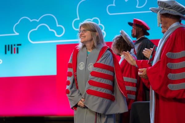 President Kornbluth stands center stage and smiles during her Inauguration with colleagues just to her left.