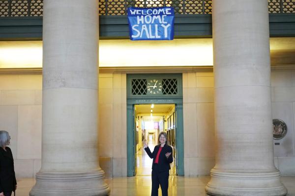 A surprised President Kornbluth is welcomed by MIT with a "Welcome Home Sally" sign that hangs in the Rogers Building lobby.