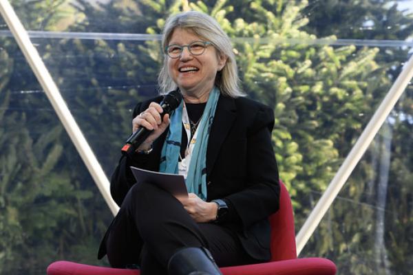 MIT President Sally Kornbluth is seated onstage with a microphone at the World Economic Forum, speaking to the audience